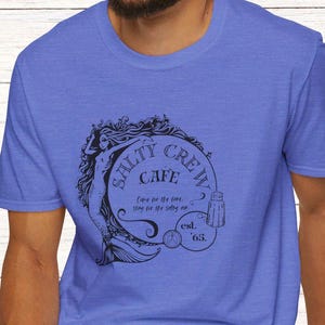 May include: A blue t-shirt with a black and white graphic of a mermaid and the text "Salty Crew Cafe Come for the food, stay for the salty air est. '65."