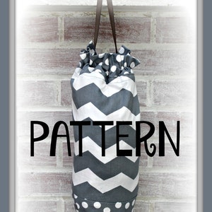 Könnte beinhalten: Eine graue und weiße Stofftasche mit Chevron-Muster und weißen Punkten, die an einer Backsteinwand hängt. Die Tasche ist mit "PATTERN" beschriftet.