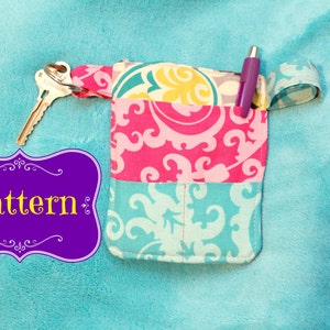 May include: A colourful fabric pouch with a key ring and a pen. The pouch has a pink, blue and yellow floral pattern. The pouch is labelled "Pattern".