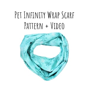 May include: A turquoise blue infinity wrap scarf with a snowflake pattern. The scarf is made of fabric and is designed for pets. The text "PET INFINITY WRAP SCARF PATTERN + VIDEO" is printed on a white background above the scarf.