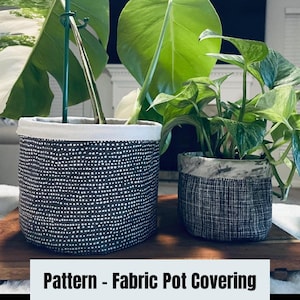 以下が含まれることがあります： 2つの布製の植木鉢カバー。1つは白のドット模様の黒、もう1つは白黒の市松模様。どちらも木製の表面の上に置かれています。