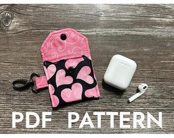 Könnte beinhalten: Eine rosa und schwarze Stofftasche mit einem Herzmuster und einem Reißverschluss. Die Tasche ist offen und ein weißes AirPod-Etui befindet sich im Inneren. Der Text "PDF PATTERN" befindet sich am unteren Rand des Bildes.