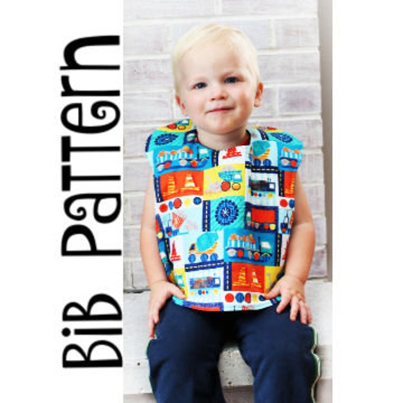 May include: A colorful bib with a construction vehicle pattern. The bib is sleeveless and has a snap closure at the neck.