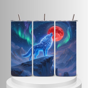 Puede incluir: Un vaso cilíndrico con el gráfico de un lobo azul aullando sobre un acantilado nevado bajo una gran luna roja y auroras boreales verdes. El diseño incluye un cielo nocturno azul oscuro lleno de estrellas y picos montañosos.