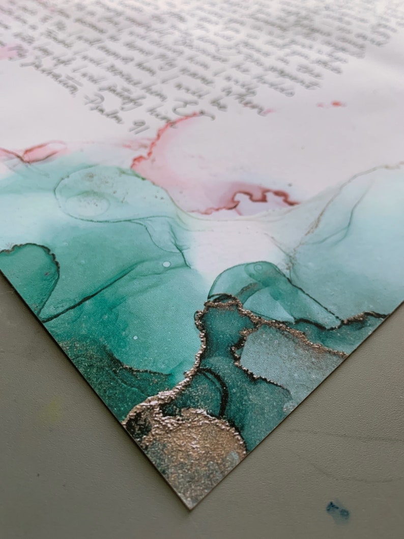 Puede incluir: Primer plano de un papel blanco con un mensaje escrito a mano en tinta negra. El papel tiene un dise&ntilde;o abstracto verde y dorado en la parte inferior.