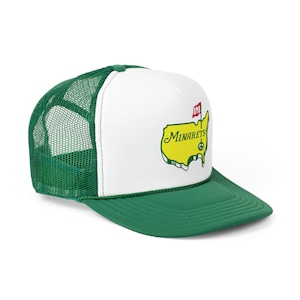Op de afbeelding: Een witte en groene truckercap met een gele omtrek van de Verenigde Staten, een rode vlag met de letters "DMB" en de tekst "MINARETS" met een vredesteken.