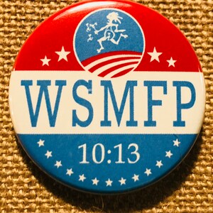 May include: A red, white, and blue button with a cartoon figure running and the text "WSMFP 10:13"