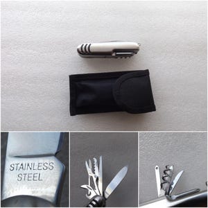 Puede incluir: Una multiherramienta de acero inoxidable con una funda negra. La herramienta incluye un cuchillo, un sacacorchos y otros implementos. Las palabras "STAINLESS STEEL" están grabadas en la herramienta.