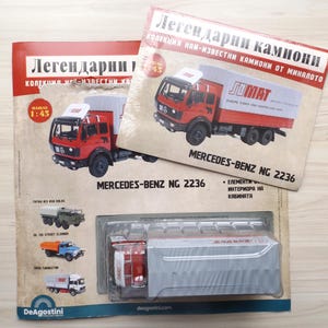 Puede incluir: Un modelo de camión Mercedes-Benz NG 2236 rojo y blanco con un remolque blanco, exhibido con dos revistas. Las revistas presentan el mismo modelo de camión y el texto "Легендарни камиони". El modelo está en una caja de plástico transparente.