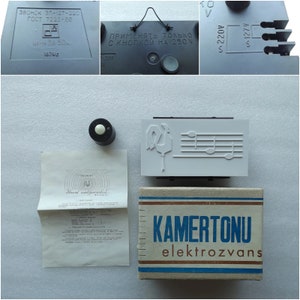 May include: A white box with the text "KAMERTONU elektrozvans" printed in blue and brown. The box contains a white doorbell with a musical note design and a black button. The doorbell is labeled "ЗВОНОК ЗП-127-220 ГОСТ 7220-66 ЦЕНА ЗР. 50к. 1870г."