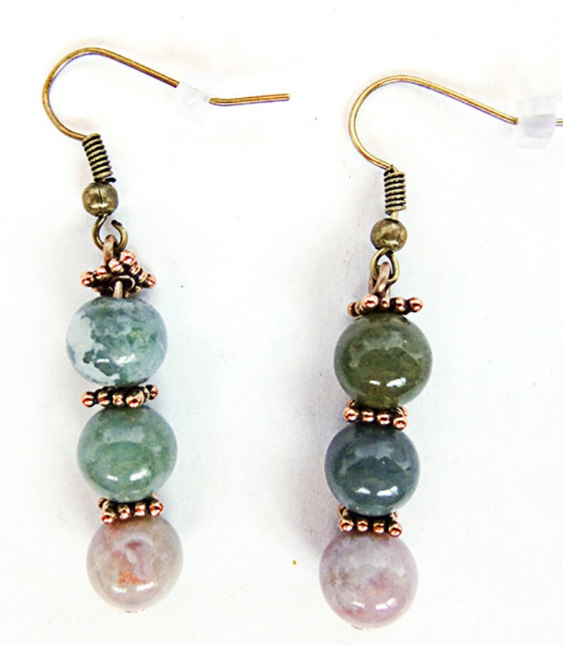 May include: A pair of dangle earrings featuring a combination of green, blue, and pink gemstone beads. The beads are separated by copper-colored decorative elements and suspended from gold-colored ear wires.