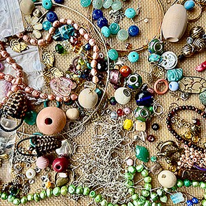 May include: A collection of colorful beads, charms, and other jewelry making supplies. The assortment includes glass beads, metal charms, wooden beads, and more.