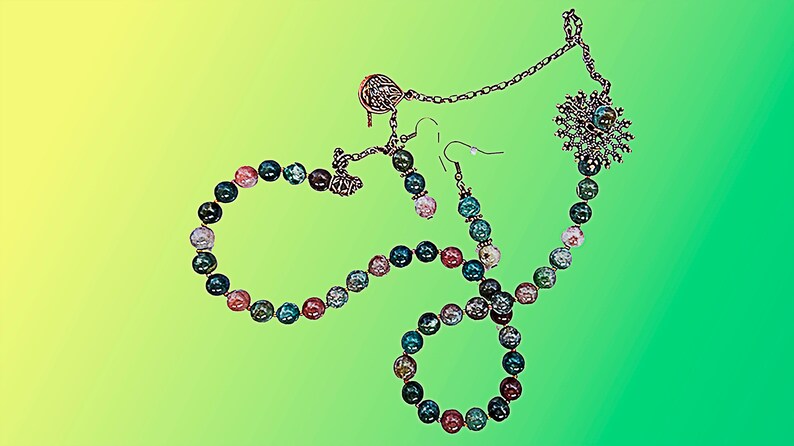 May include: A jewelry set featuring a necklace, bracelet, and earrings. The necklace and bracelet are made of colorful, round beads in shades of blue, pink, and green. The earrings have matching beads. The set includes silver-toned metal accents.