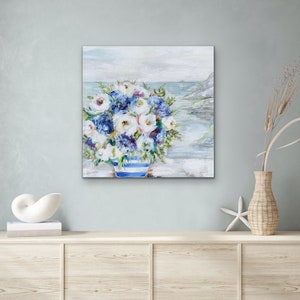 May include: A painting of a bouquet of white and blue flowers in a blue and white striped vase. The flowers are in front of a seascape with a cloudy sky.