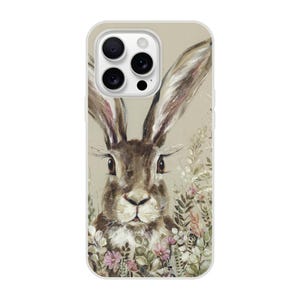 May include: A phone case featuring a detailed illustration of a brown rabbit with long ears, surrounded by delicate flowers and foliage. The artwork has a painterly style with soft colors and textures, set against a neutral background.