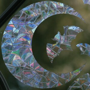 May include: A stained glass window with a crescent moon and a bat design. The glass is iridescent and has a mosaic pattern.