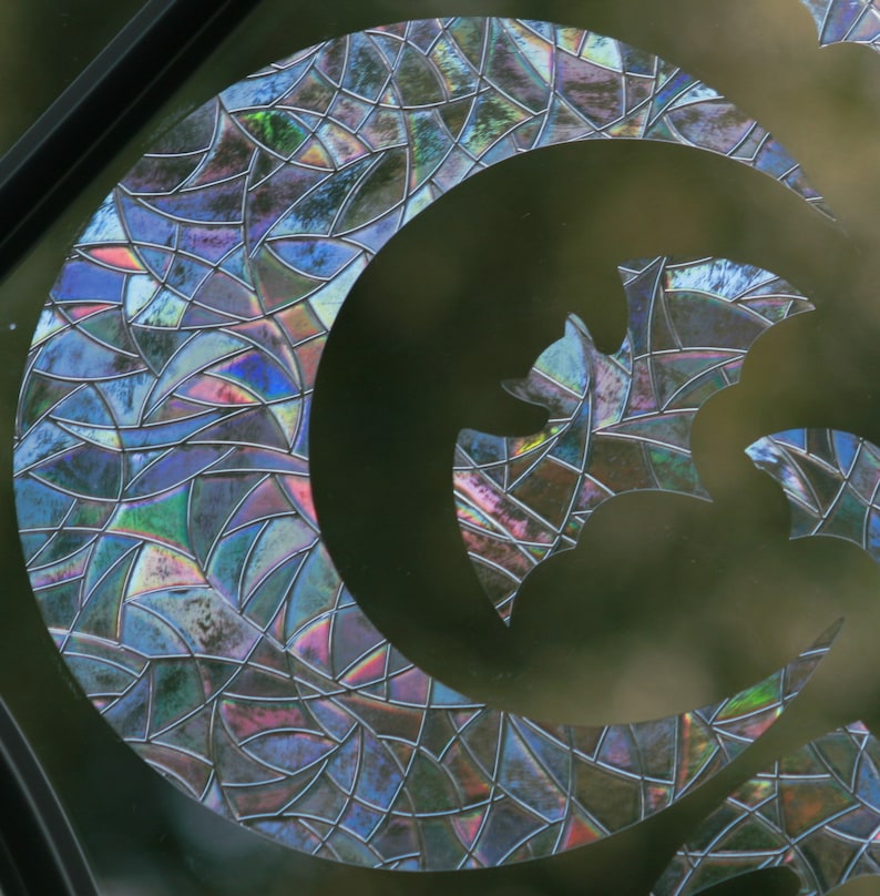 May include: A stained glass window with a crescent moon and a bat design. The glass is iridescent and has a mosaic pattern.