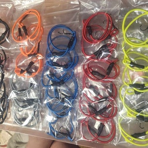 May include: Assortment of colorful elastic bands with black hooks, packaged in clear plastic bags. The bands are in various colors, including orange, blue, red, and yellow.