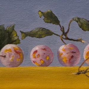 May include: Five pink plums with yellow and red markings sit on a yellow surface. Green leaves with brown stems are behind the plums.