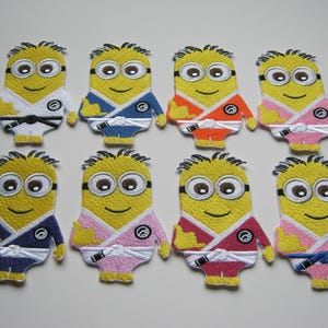 Op de afbeelding: Acht geborduurde strijkpatches met een geel minion-personage dat een karate-uniform draagt in verschillende kleuren. De minion draagt een witte band en heeft een zwart ooglapje. De patches zijn ongeveer 5 cm hoog.