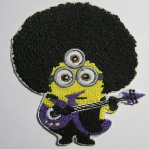 May include: A yellow minion with a black afro, three eyes, and a purple electric guitar. The minion is wearing a purple shirt and black pants.