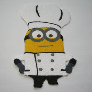 May include: A yellow and white felt applique of a minion wearing a white chef's hat and a white chef's coat with black buttons.