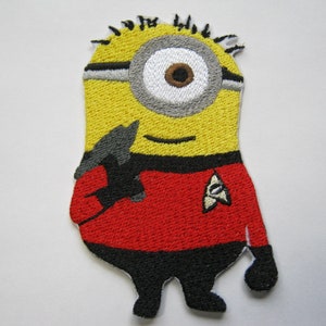 May include: Embroidered patch of a yellow Minion character in a red Star Trek uniform. The patch features a large eye, black gloves, and a Starfleet insignia. The patch is designed for application on clothing or accessories.