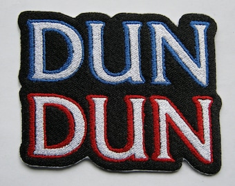 May include: A black fabric patch with the word "DUN" in white, blue, and red lettering, stacked on top of the same word in red, white, and black lettering.