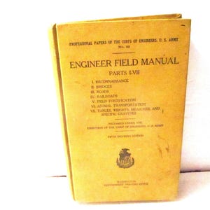 May include: A yellow hardcover book titled Engineer Field Manual Parts I-VII, Professional Papers of the Corps of Engineers, U.S. Army, No. 29. The cover lists seven parts including reconnaissance, bridges, roads, railroads, and field fortification.