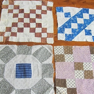 May include: Four vintage quilt blocks in various patterns and colors. One block features a checkerboard design in brown and white. Another has a blue and white geometric pattern. The other two blocks have floral and geometric patterns in shades of gray, brown, and lavender.