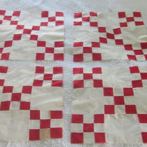 May include: Four square fabric quilt blocks featuring a red and white checkerboard pattern. Each block is constructed from smaller red and white squares arranged in a grid, creating a repeating geometric design across all four pieces of fabric.