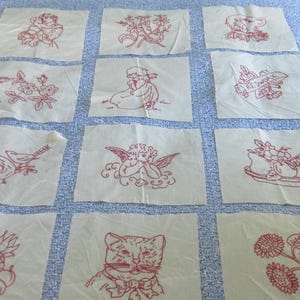Puede incluir: Doce parches cuadrados de tela blanca con bordados en hilo rojo que incluyen un niño, flores, un perro, un pájaro en un nido, un ángel, un cuenco de frutas, un gato y girasoles. Un parche incluye el texto MY REDWORK.