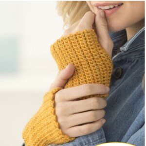 May include: A close-up of a person wearing a yellow crocheted hand warmer. The hand warmer is made with a simple stitch pattern and has a ribbed cuff. The image also includes the text "CA76".