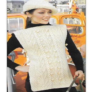 May include: A white knitted tabard waistcoat and beret knitting pattern with a model wearing the finished garment. The pattern number is K401.