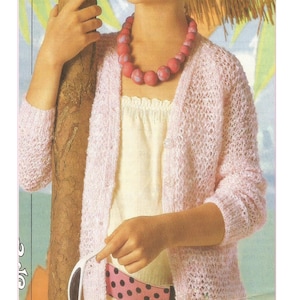 May include: A pale pink, open-stitch cardigan with button fastenings. The image shows a person wearing the cardigan over a cream top and a pink polka-dot belt. The text "Odd Pin Cardigan Knitting Pattern" is at the top of the image.