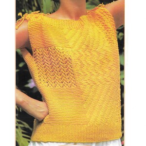 Può includere: Un top di maglia giallo con un design a patchwork. Il top ha una scollatura rotonda ed è senza maniche. Il modello è K209.
