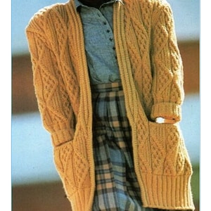 May include: A long, brown cable knit cardigan with pockets. The cardigan is open in the front and has a cable knit pattern. The pattern number K332 is visible at the bottom of the image.