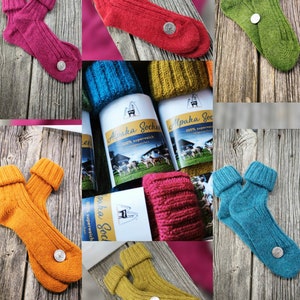 Könnte beinhalten: Eine Auswahl an farbenfrohen Alpaka-Wollsocken in verschiedenen Farbtönen, darunter Pink, Rot, Grün, Gelb und Blau. Jedes Paar hat ein geripptes Design und ein kleines, rundes Emblem. Die Socken werden auf einer Holzoberfläche präsentiert.