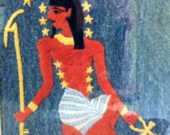 May include: A red and blue embroidered image of a kneeling figure with a staff and an ankh. The figure is surrounded by yellow stars on a blue denim background.