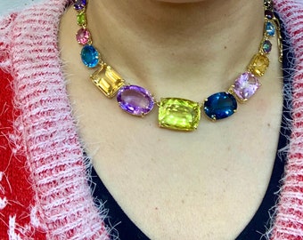 May include: A gold necklace with a variety of colorful gemstones, including amethyst, topaz, and sapphire.