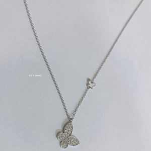 May include: A silver chain necklace with two butterfly pendants. The larger pendant is covered in small, clear stones. The smaller pendant is plain silver.