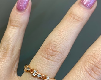 May include: A gold ring with a delicate design of leaves and small clear stones.