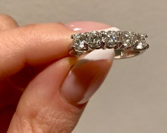 May include: A silver band ring with five round diamonds set in a row.