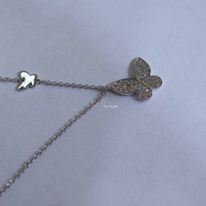 May include: A silver necklace featuring a dainty butterfly pendant. The butterfly is embellished with shimmering clear stones.