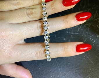 May include: A gold tennis bracelet with a row of round, clear diamonds.