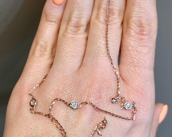 May include: A delicate rose gold chain necklace with small clear gemstones. The necklace is layered and features a total of six gemstones.