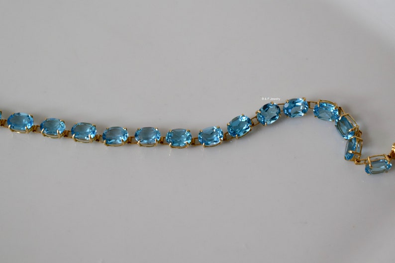 May include: A gold chain bracelet with oval-shaped blue topaz gemstones.