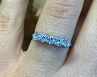 May include: A silver band with six round, clear gemstones set in a row.