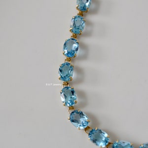 May include: A gold chain bracelet with oval-shaped blue topaz gemstones.