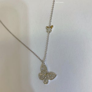 May include: A silver chain necklace with a small butterfly charm at the top and a larger butterfly charm with clear stones at the bottom.  B & F Jewelry is printed on the image.